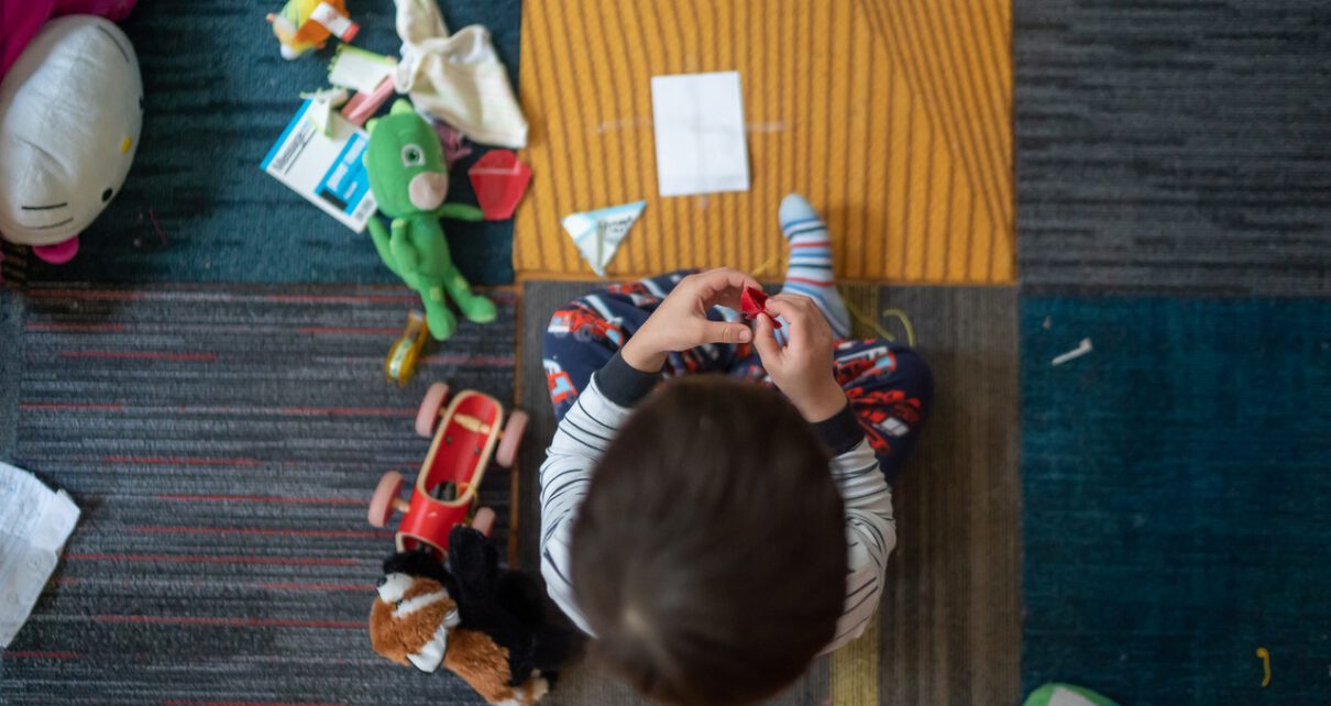 Chłopiec bawi się na dywanie zdalnie sterowanymi zabawkami