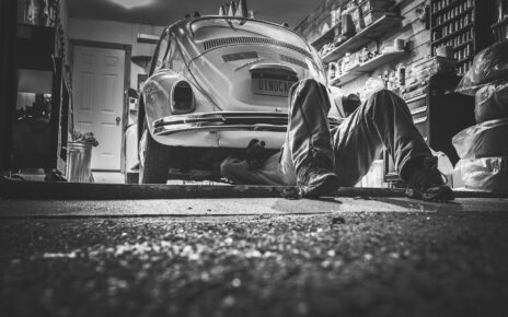 Mężczyzna naprawia samochód i lezy na posadzce w garażu