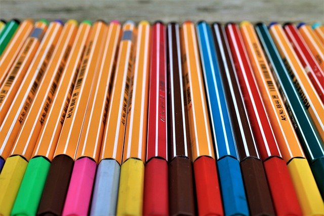 Kolorowe cienkopisy leżą poukładane na stole