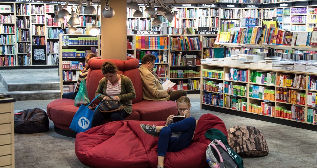Ludzie w bibliotece lub czytelni czytający książki po angielsku