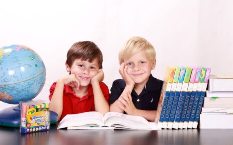 Dwuch chłopców siedzi przy biurku obok wyprawki szkolej
