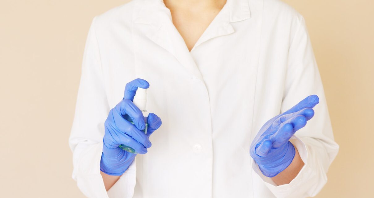 Kobieta w fartuchu medycznym dezynfekuje dłonie