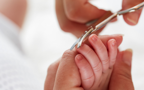 Kobieta obcina paznokcie dziecku nożyczkami dla niemowląt