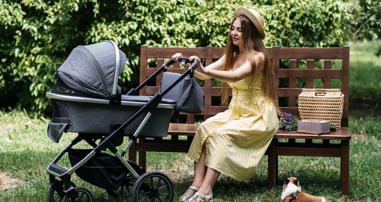 Kobieta wozi w wózku swoje dziecko po parku